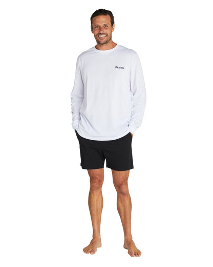 A male model wearing a white long sleeve t-shirt with the Okanui Walk Short in black colour.