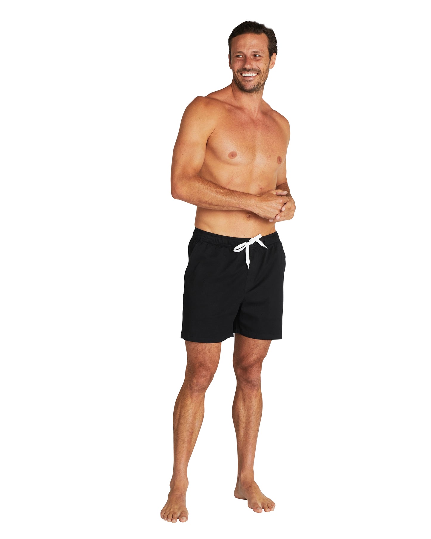 A male model smiling and posing wearing the Okanui Walk Shorts.