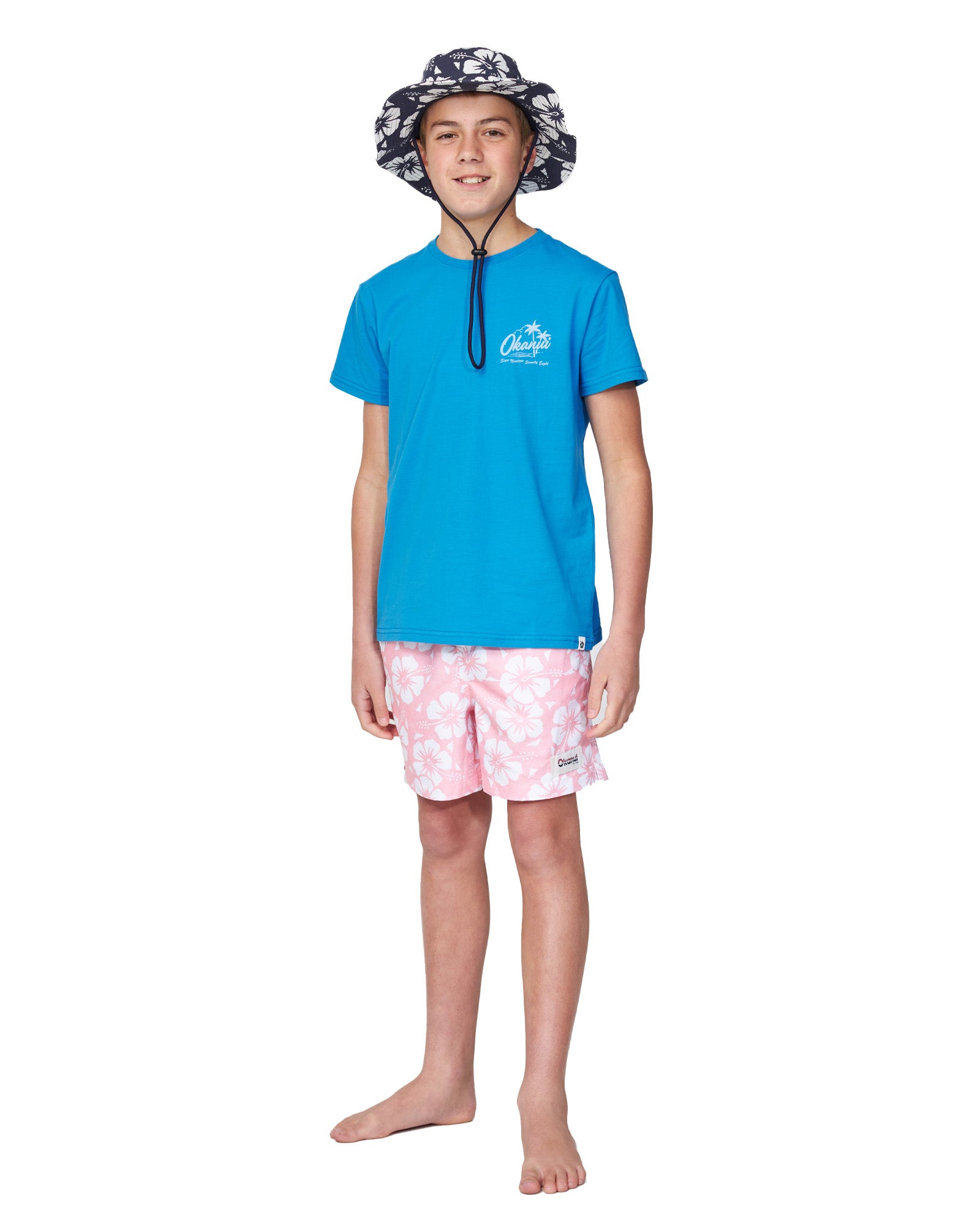 Full body front view of a boy model wearing the Okanui Classic Boonie Hat in Hibiscus Navy Print