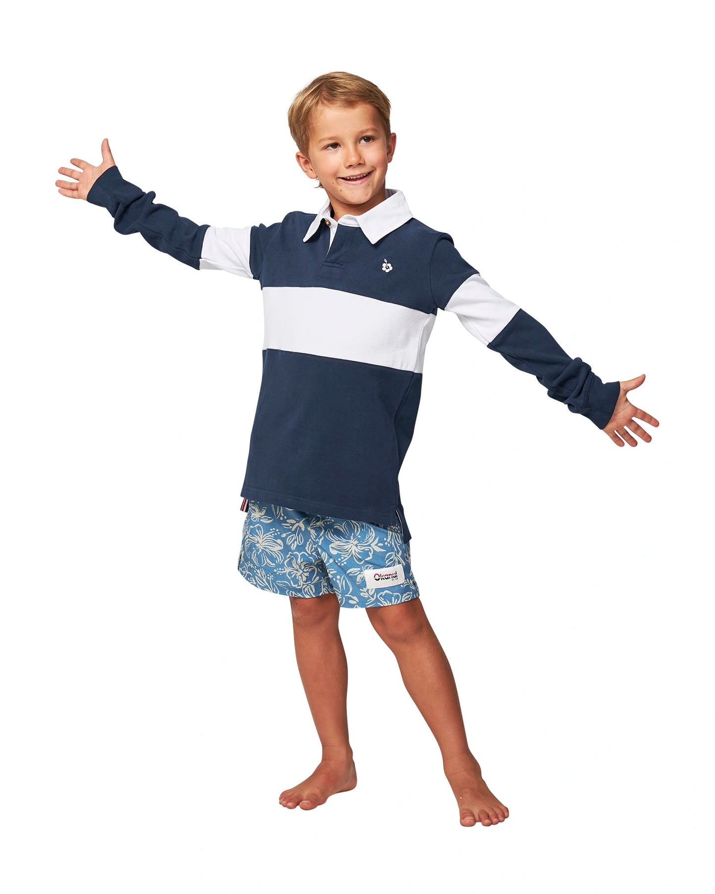 Full body front view of a little  boy wearing the Okanui Heritage Rugby Top and Jumpers in Navy/White