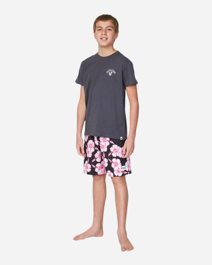 Full body front view of boy in gray shirt paired with the Okanui kids boardrider boardshort in Black Pink