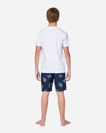 Full body back vew of a boy in white thsirt wearing the Okanui boardrider board shorts for kids in White Navy