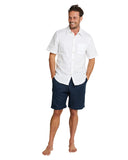 A male model wearing a white short sleeve button up shirt and the Okanui men's linen shorts.