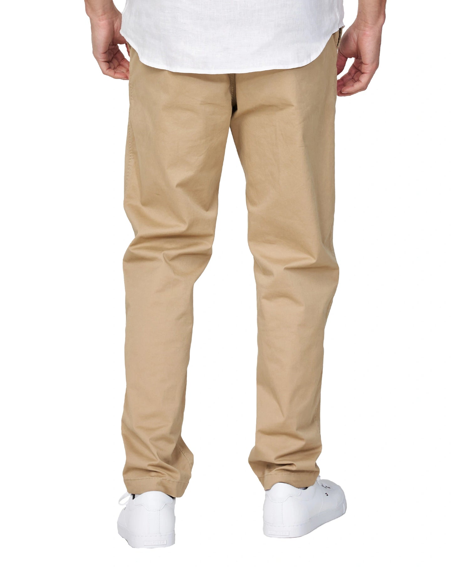 Half-body back view of the Okanui Men's Chino Pants in sand color worn by a model with shirt and shoes.