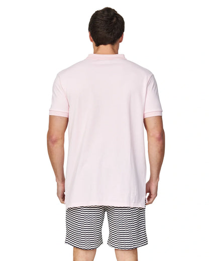 A closer back view of a male model wearing a black and white striped short and the Okanui Classic Polo Shirt in pale pink colour.