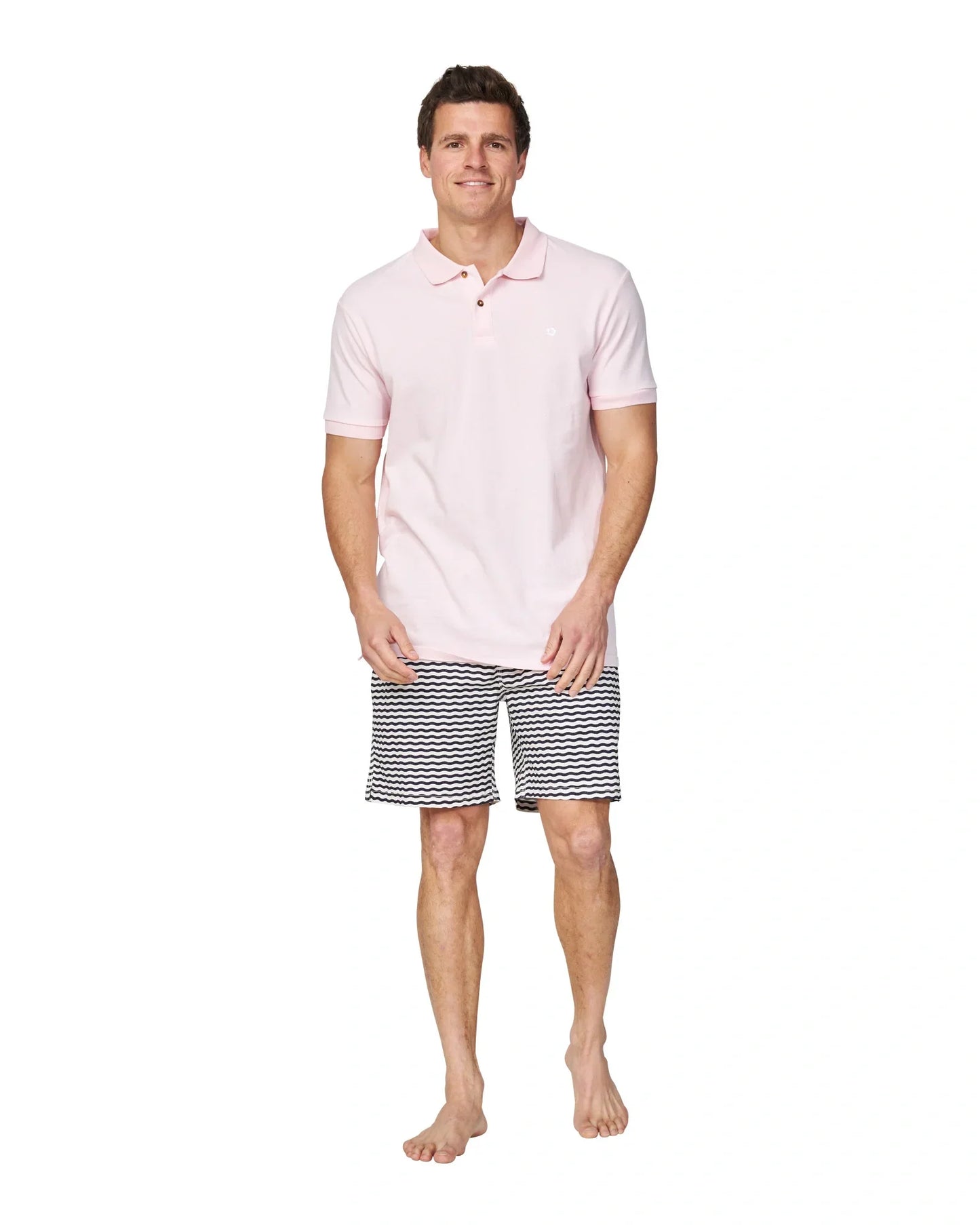 A full body length view of a male model wearing a black and white striped short and the Okanui Classic Polo Shirt in pale pink colour.