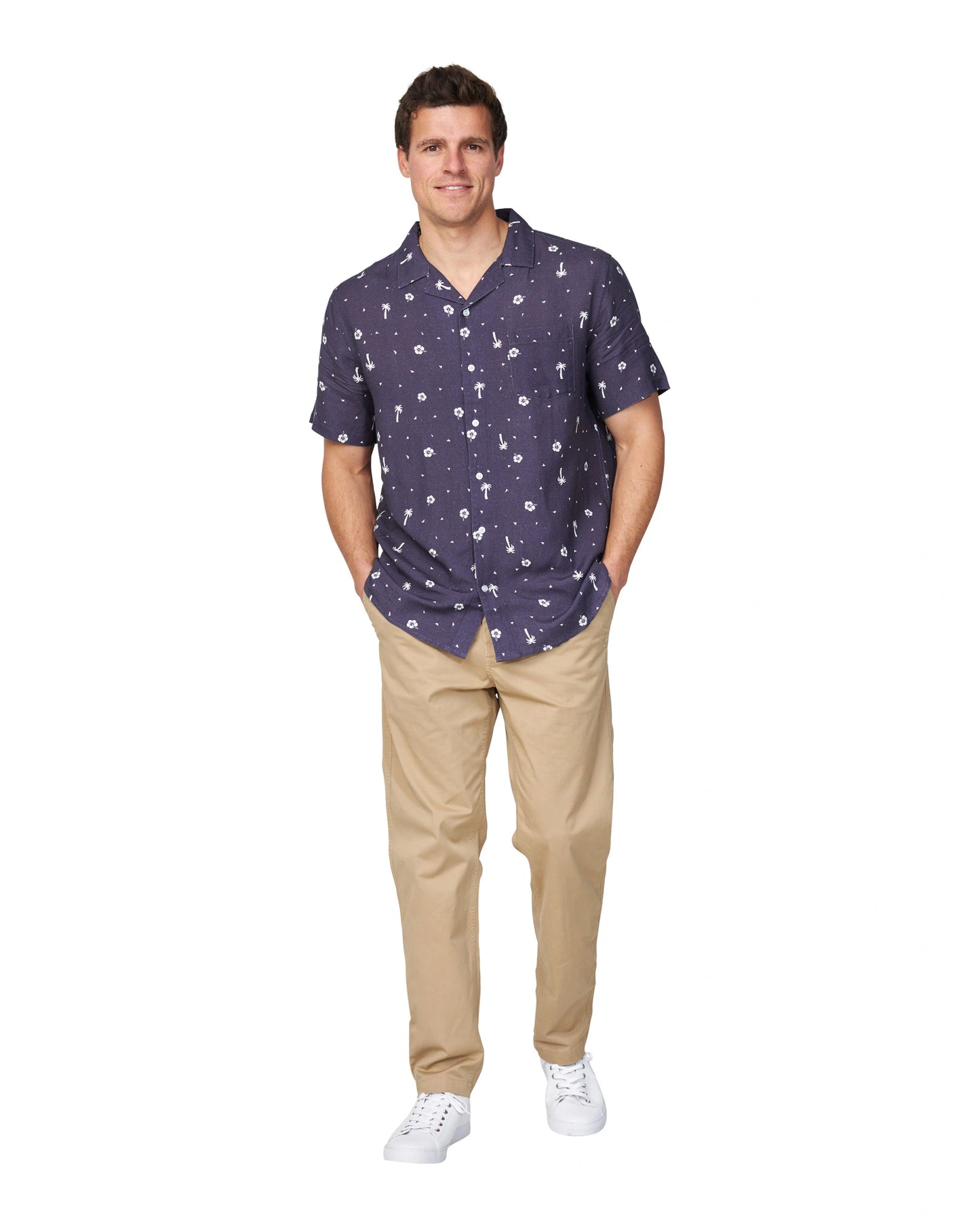 A male model with his hands in the pockets of his pants wearing the Okanui Icons Coastal Short Sleeve Aloha Shirt for men in navy colour.