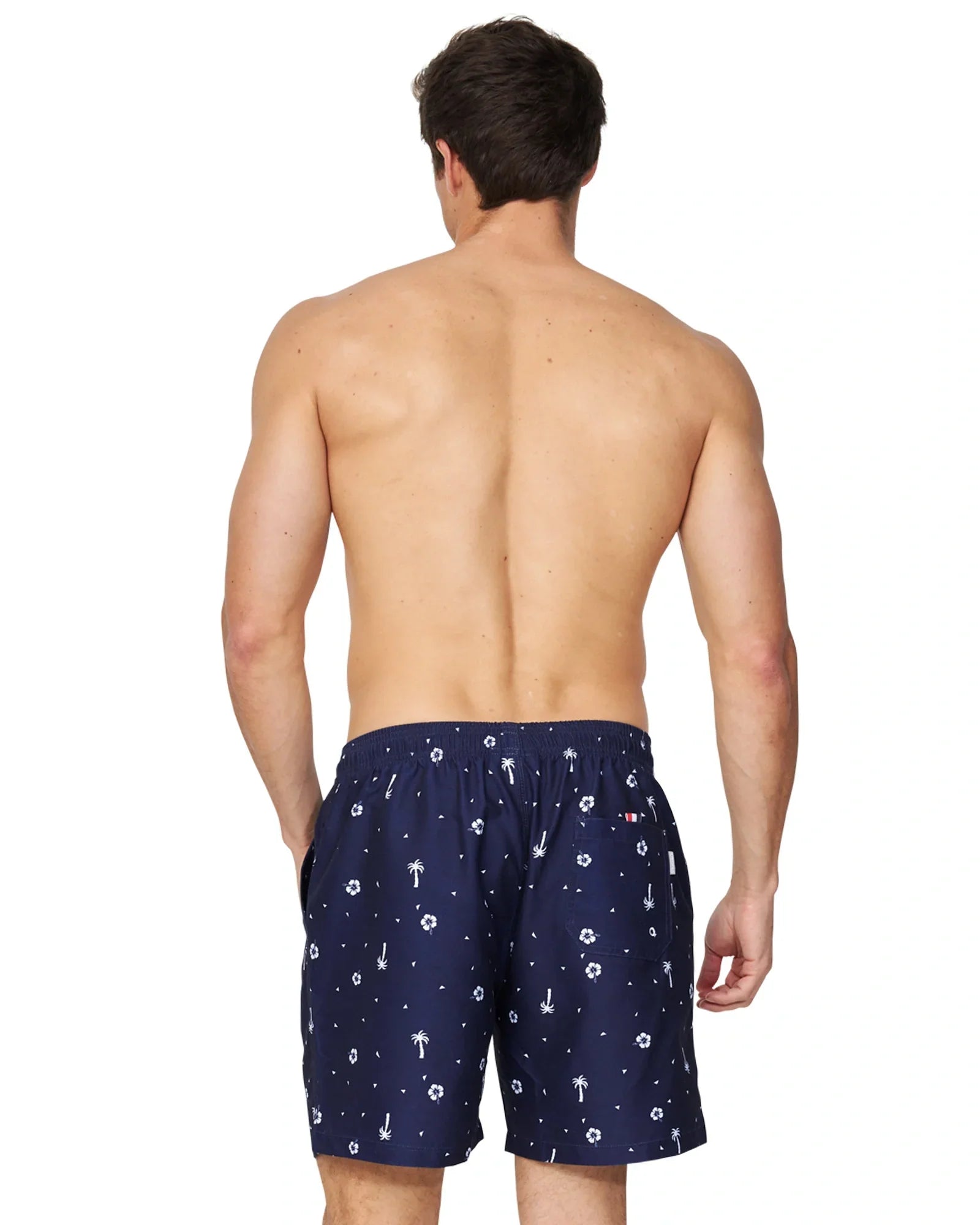 A closer back view of a male model wearing the Okanui Icons Swimshorts in navy colour with his hand in a pocket.