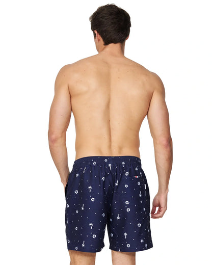 A closer back view of a male model wearing the Okanui Icons Swimshorts in navy colour with his hand in a pocket.
