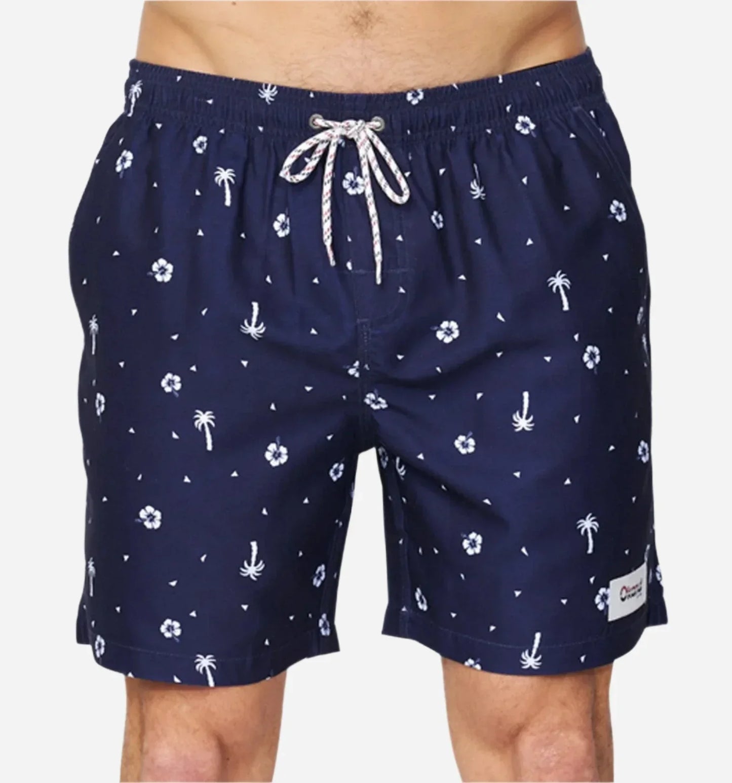 The Okanui Icons Swimshort in navy colour featuring small white prints of Hibiscus flowers and coconut trees with a logo patch on the left leg.