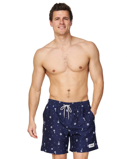 A closer front view of a male model wearing the Okanui Icons Swimshorts in navy colour with his hand in the pocket.