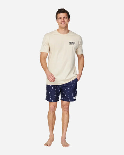 A male model wearing a birch color tee from Okanui and the Okanui Icons Swimshorts for men in navy color.