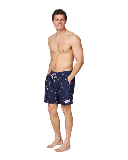 A male model wearing the Okanui Icons Swimshorts in navy colour with his hands in the pockets.