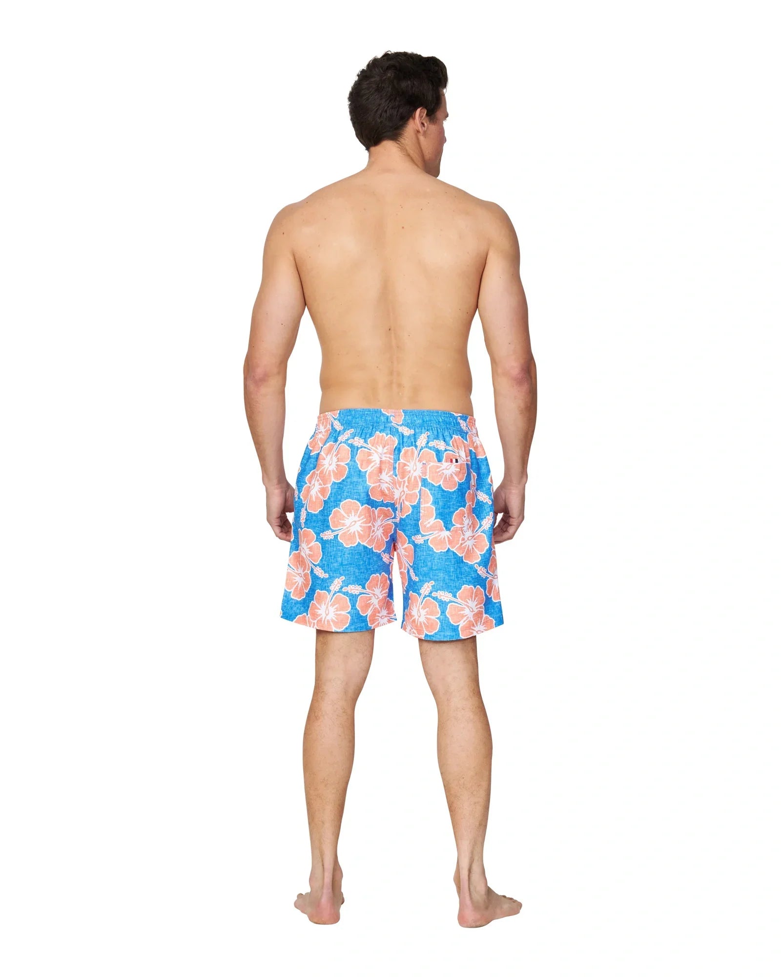 A full body back view of a male model wearing the Okanui Way Back When Swimshorts in Bright Blue/Orange Colour.