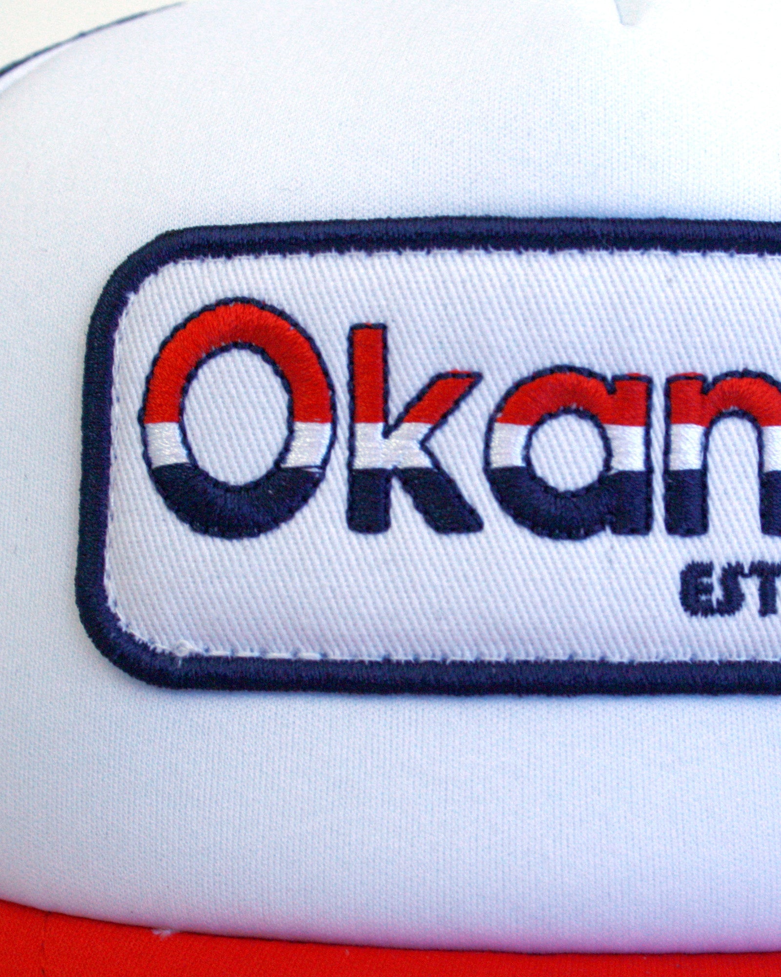 Closeup view of the Okanui Old School Trucker Cap Logo  in Red White Navy combination color