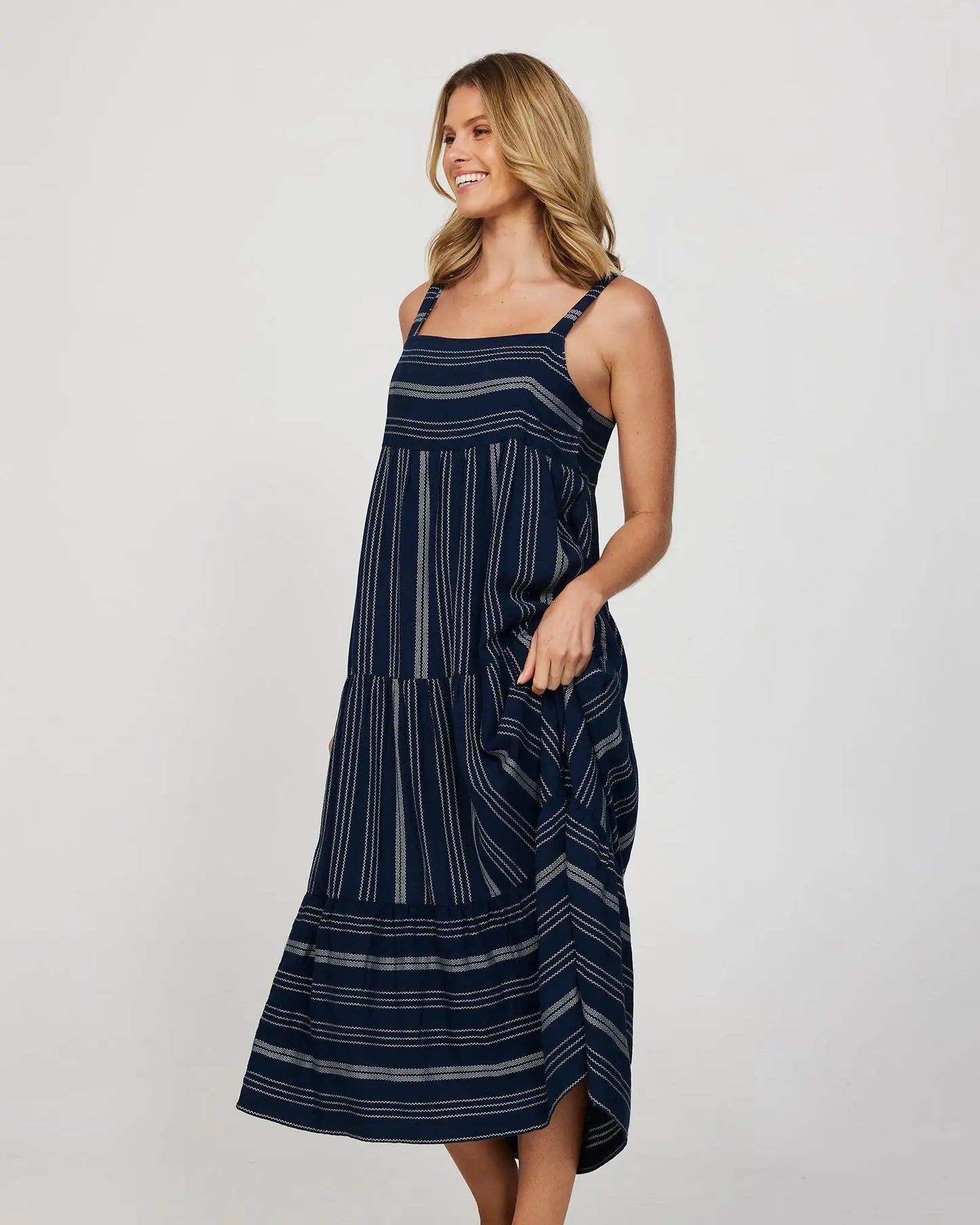 Full front slightly side view of a female model wearing a long navy Okanui Dress.