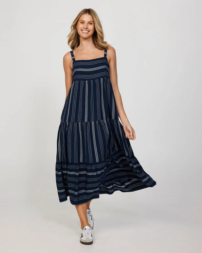 Full front view of a smiling female model wearing a long navy Okanui Dress.