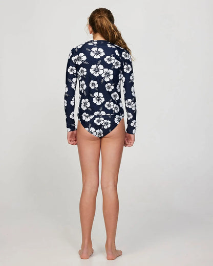 Full body back view of a girl model wearing the Okanui Longsleeve swimsuit for Girls in Hibiscus Navy