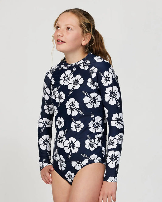 Closeup front view of a girl model wearing the Okanui Longsleeve swimsuit for Girls in Hibiscus Navy