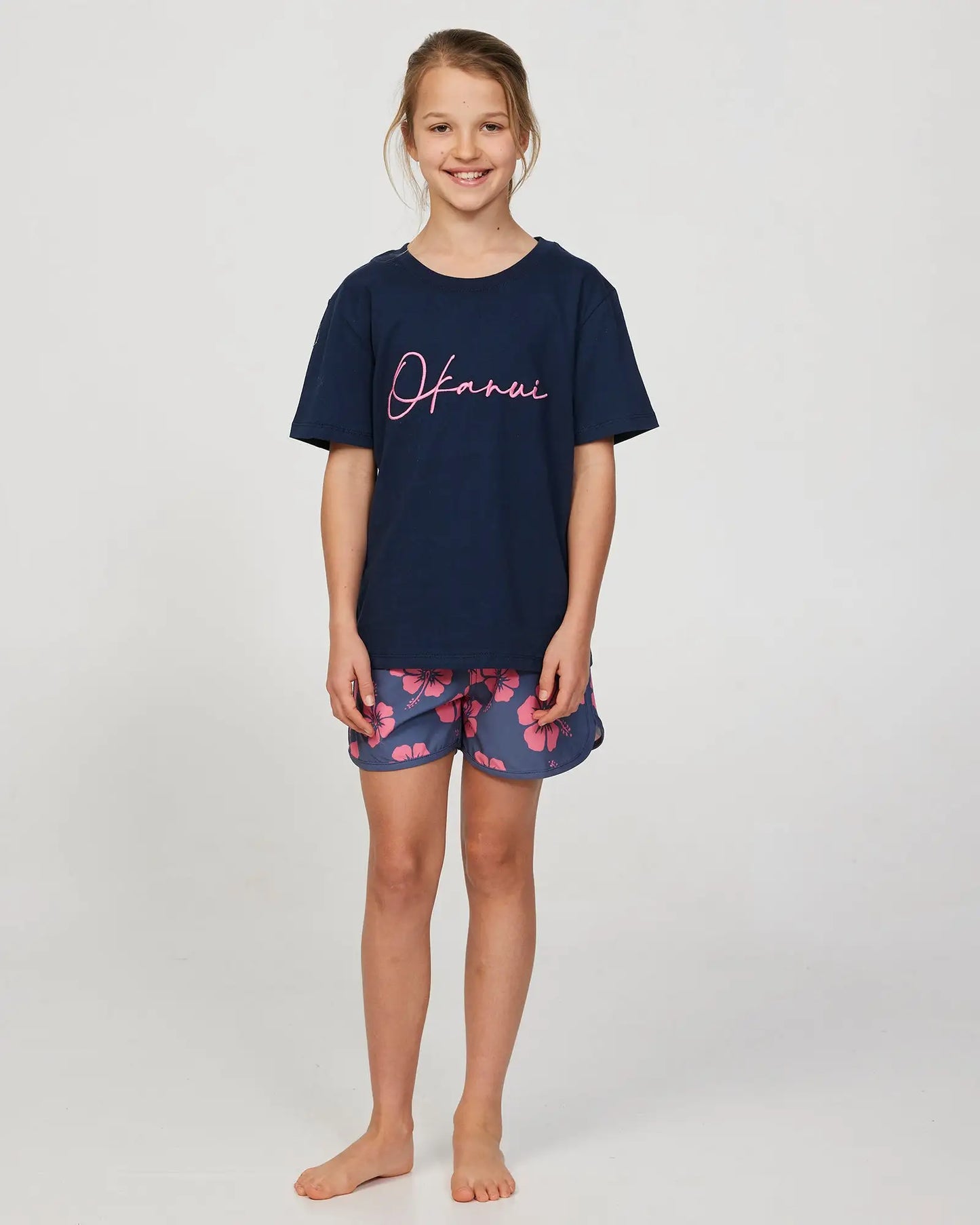 Full body front view of a little girl model wearing the Okanui Signature Tee T-shirt in Steel