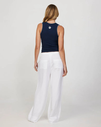 Back view of a female model wearing a navy Okanui tank top and white loose pants.