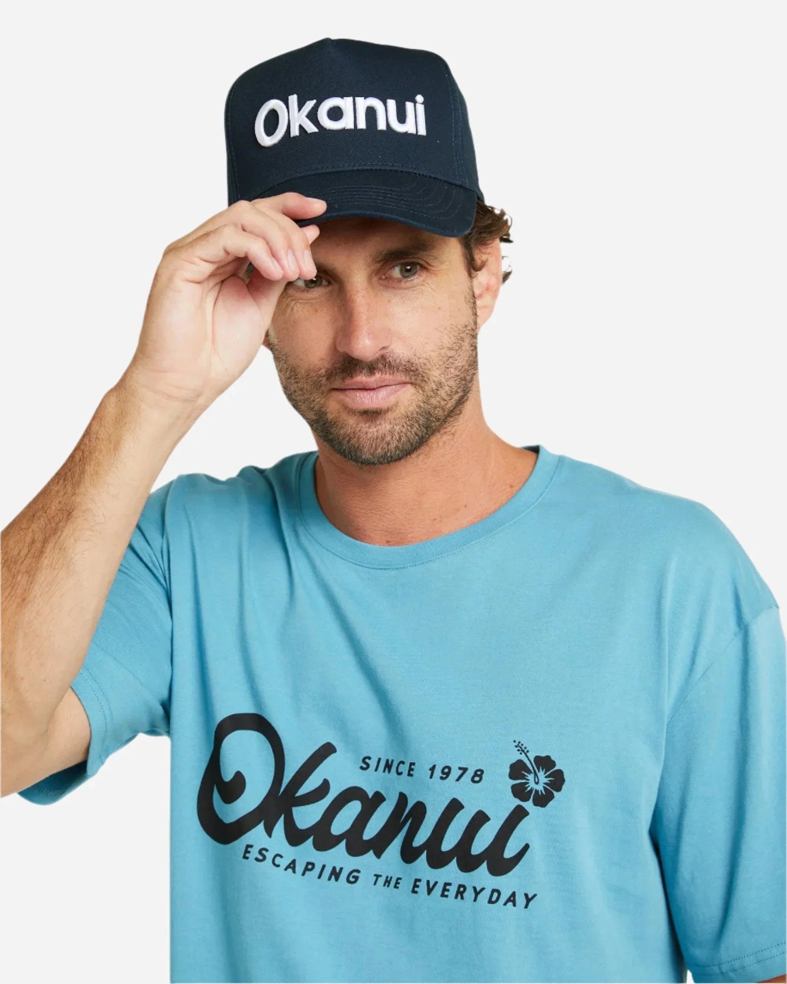 Front view of a male model wearing  the Okanui Snapback Trucker Cap in Navy Color