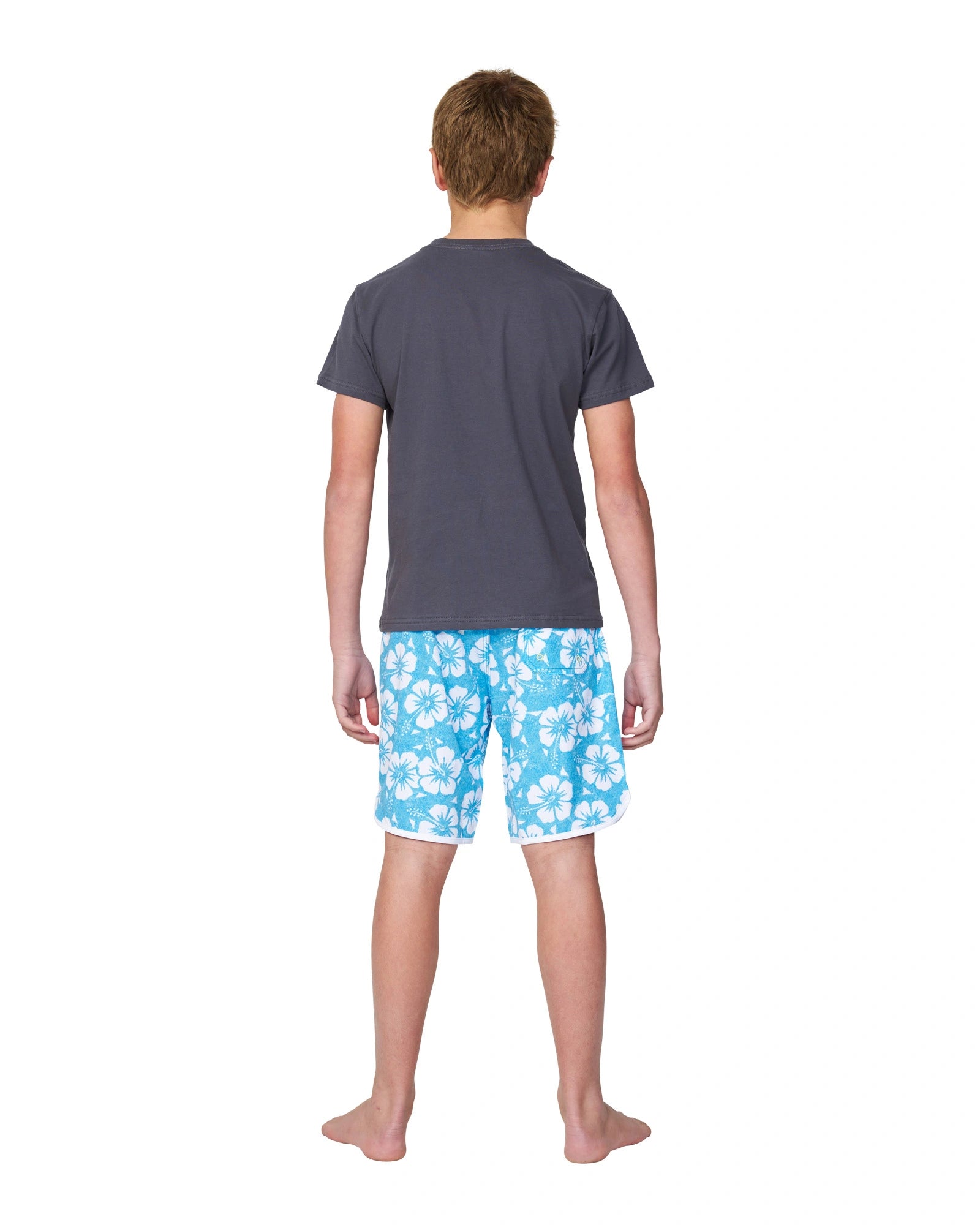 Full body back view of a boy wearing the Okanui Logo Tee T-shirt in Washed Black paired with the Okanui hibiscus aqua swim short