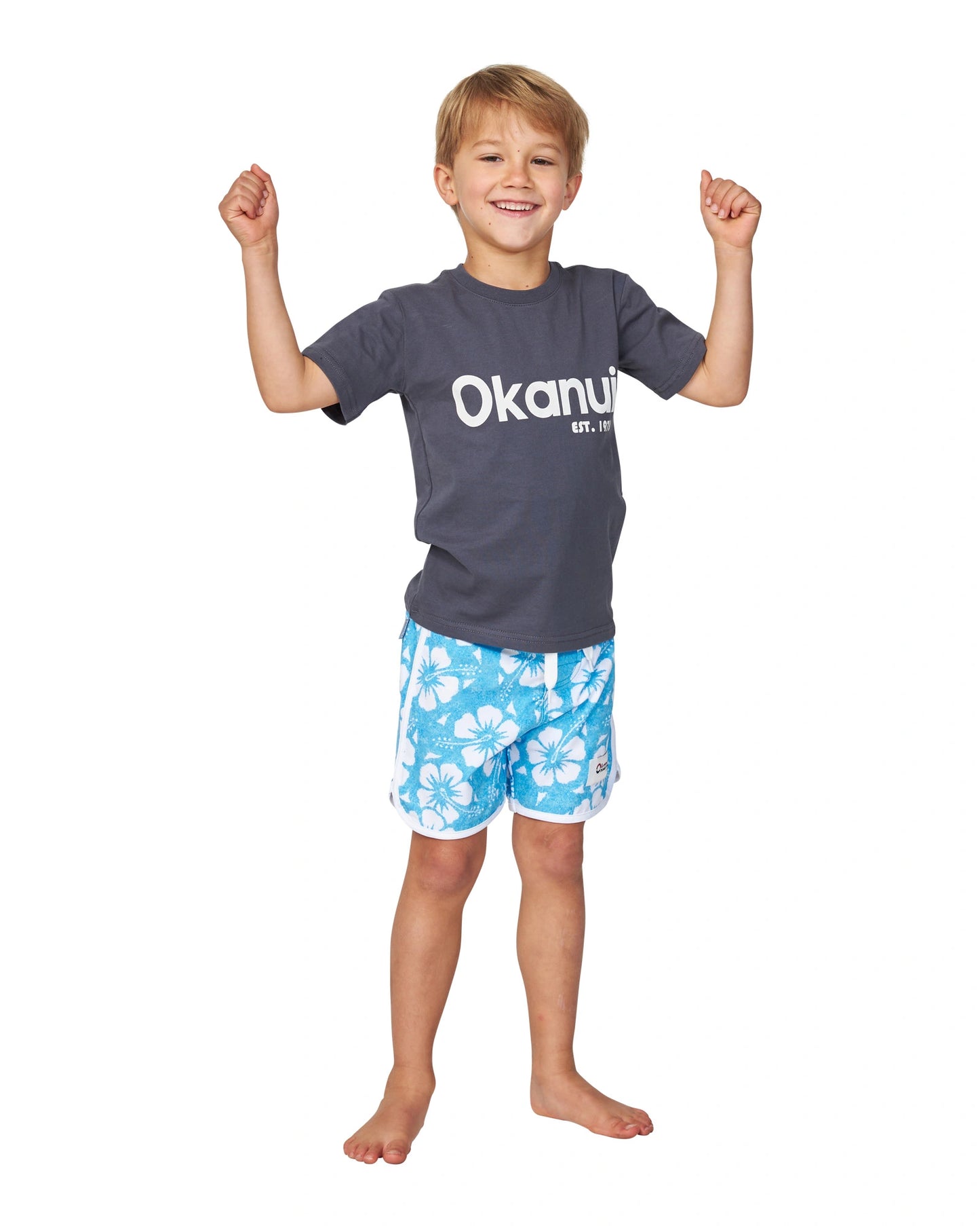 Full body front view of a little boy flexing biceps pose wearing the Okanui Logo Tee T-shirt in Washed Black