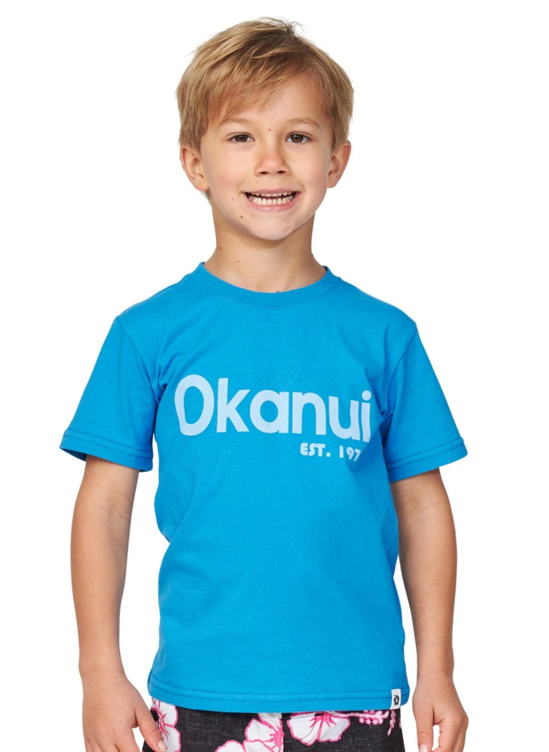 Closeup front view of a little boy wearing the Okanui Logo tee T-shirt in Washed Blue