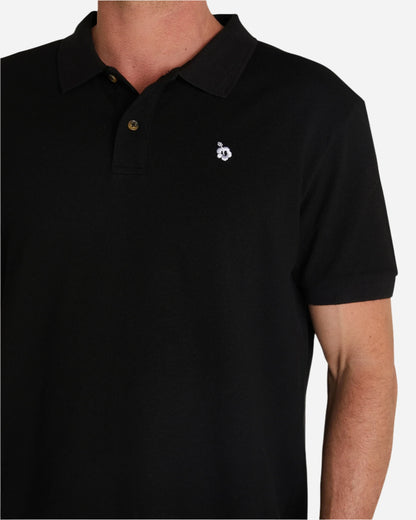 A closer look at the Okanui Classic Polo Shirt in black showcasing the embroidered white Hibiscus flower.