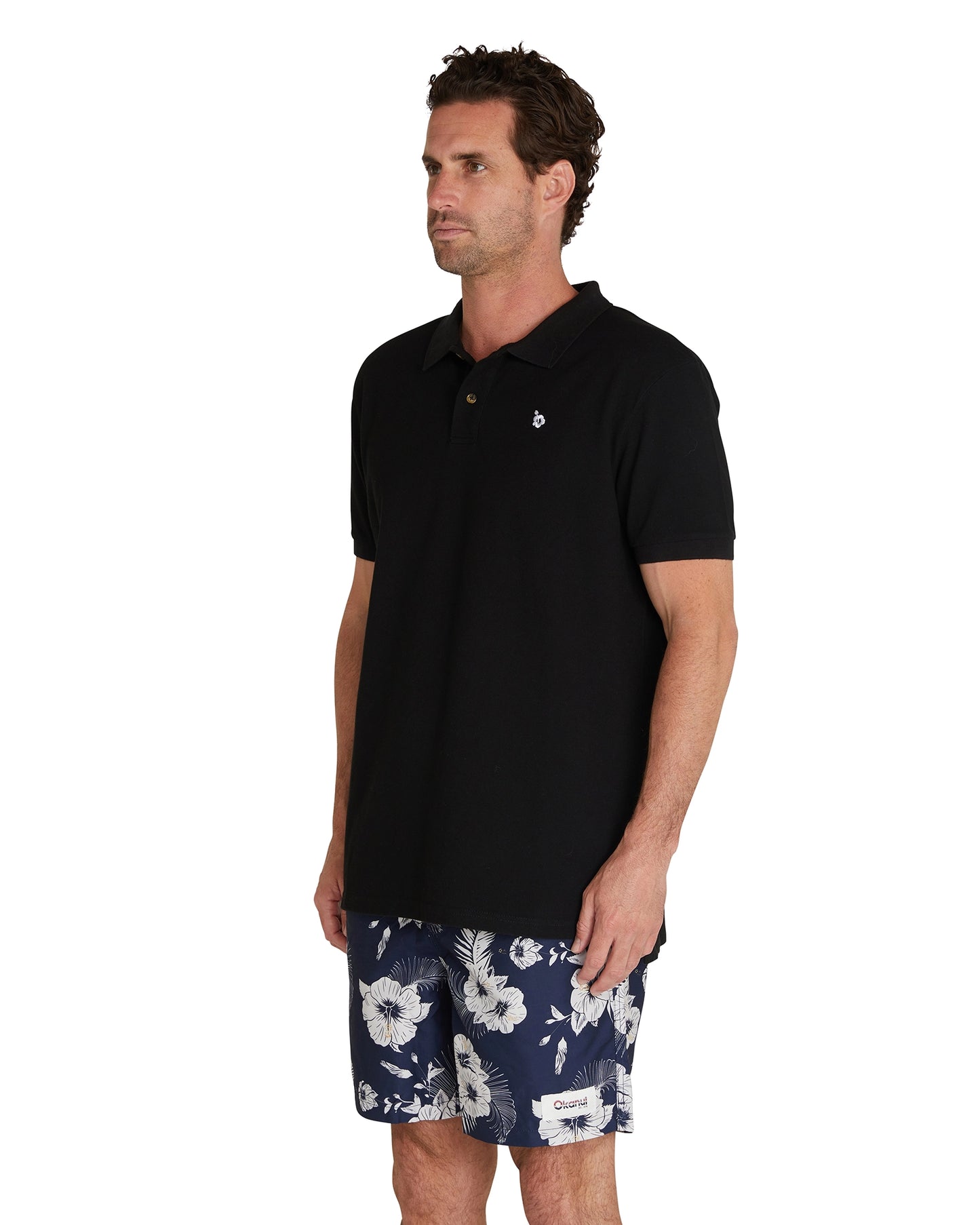 Side view of a male model wearing the Okanui Classic Polo Shirt in black.