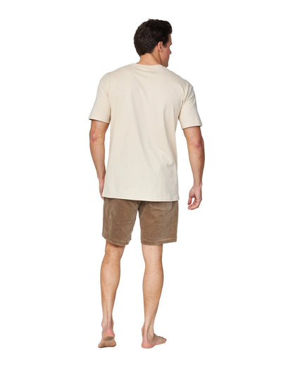 A full body back view of a male model wearing the Okanui Staple Tee in Birch color.