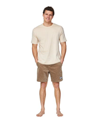 A full body view of a male model wearing the Okanui Staple Tee in Birch color.