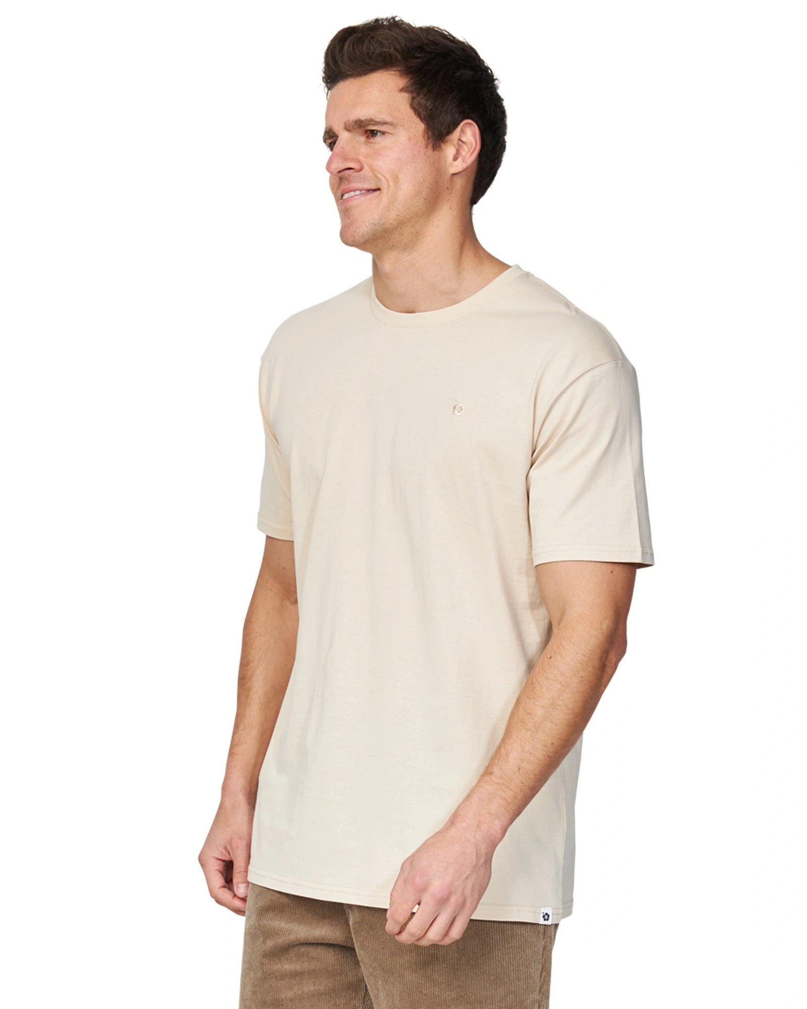 A side view of a male model wearing the Okanui Staple Tee in Birch color.