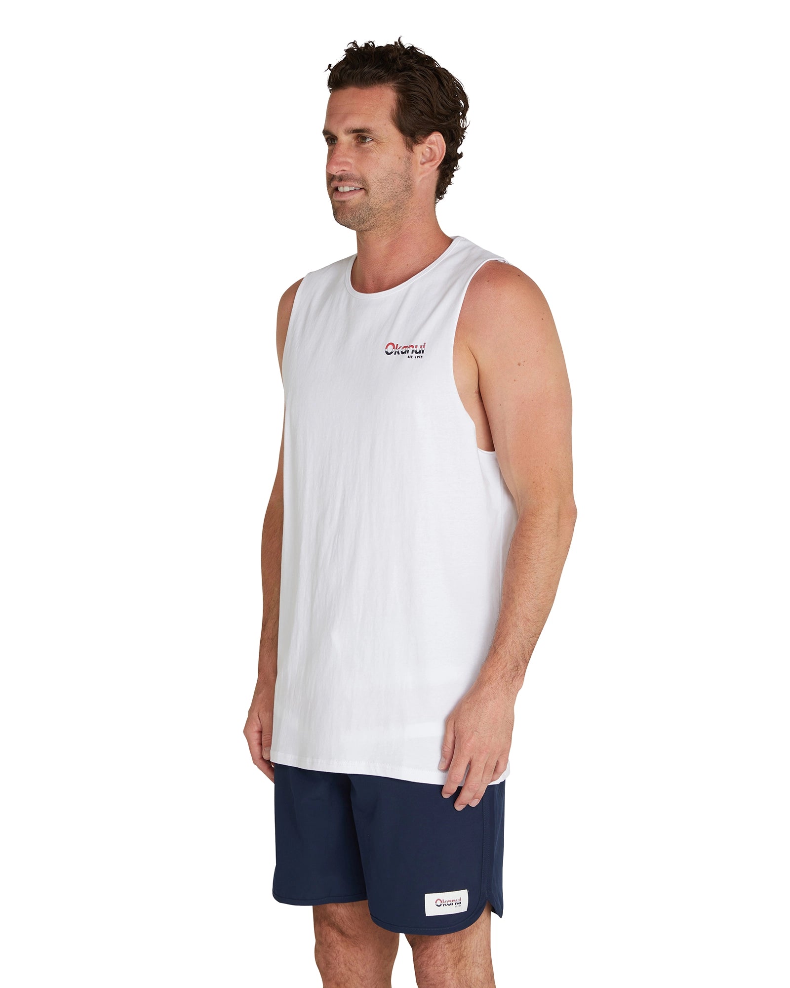 A closer side view of the male model wearing the Okanui Classic Logo Tank Top showcasing the Okanui logo on the left chest.