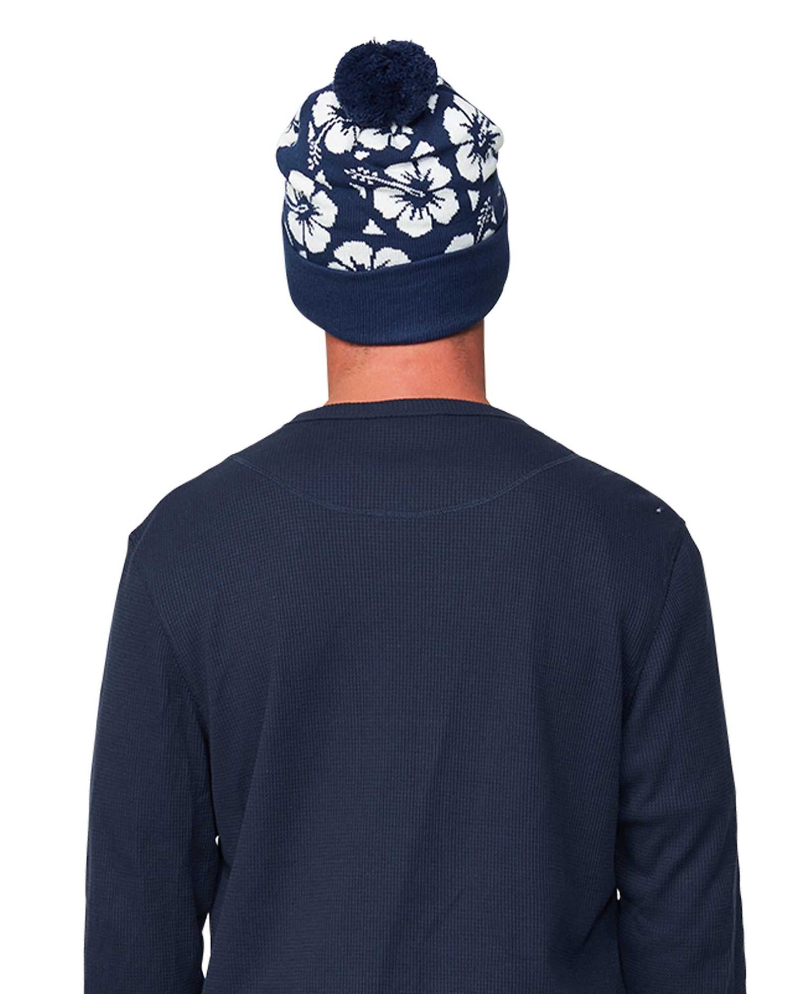 Back view of a male model wearing the Okanui Hibiscus Rib knit Pom Pom beanie hat in Navy color