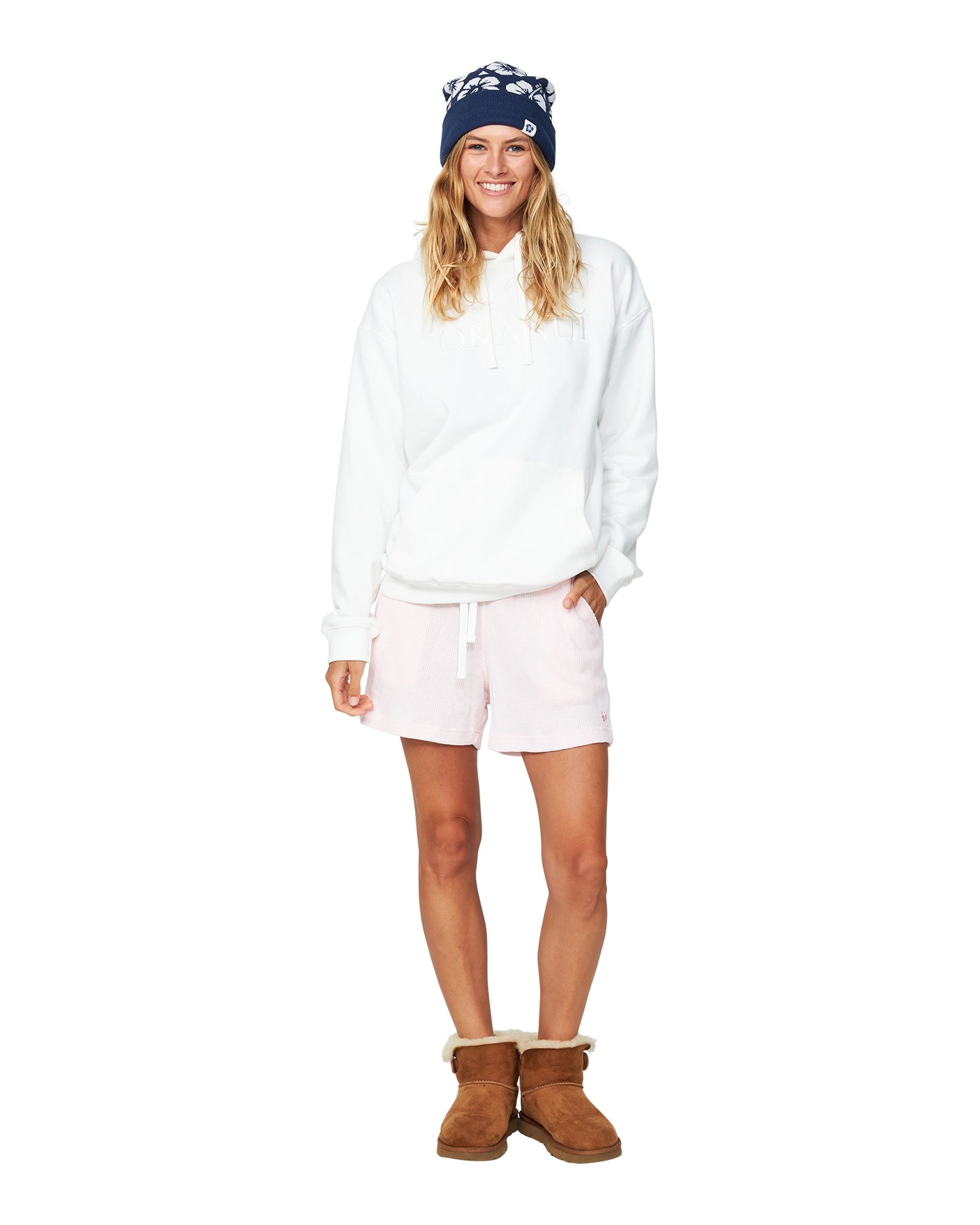 Female Model in a white long sleeve shirt and boots paired with the Okanui Hibiscus Rib knit Pom Pom beanie hat in Navy color