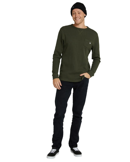 Full body of a male model one hand in pocket pose wearing the Front view of a male model wearing the Okanui Fisherman's Rib knit beanie hat anti anti black variant