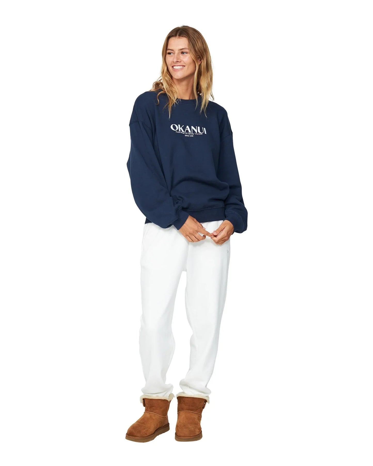 Okanui Winter fleece in navy blue colored with white pants and brown boots. 