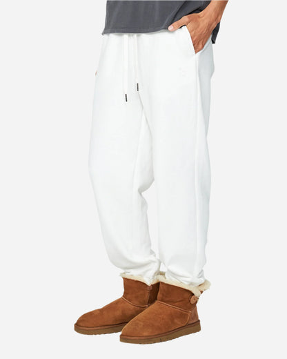 A woman is wearing a white track pants with grey shirt and brown boots. 