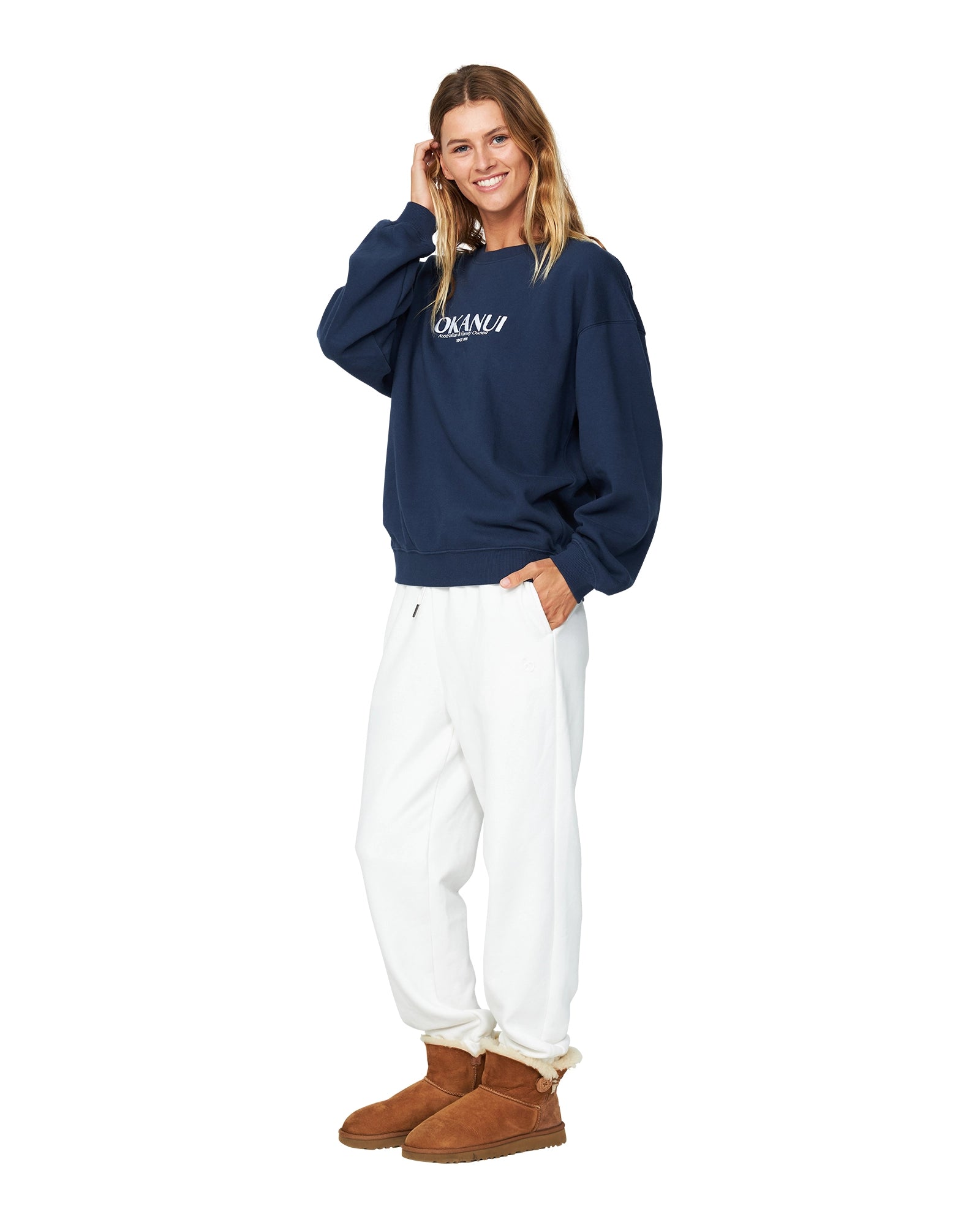 A woman is wearing a navy blue sweater and a white track pants. 