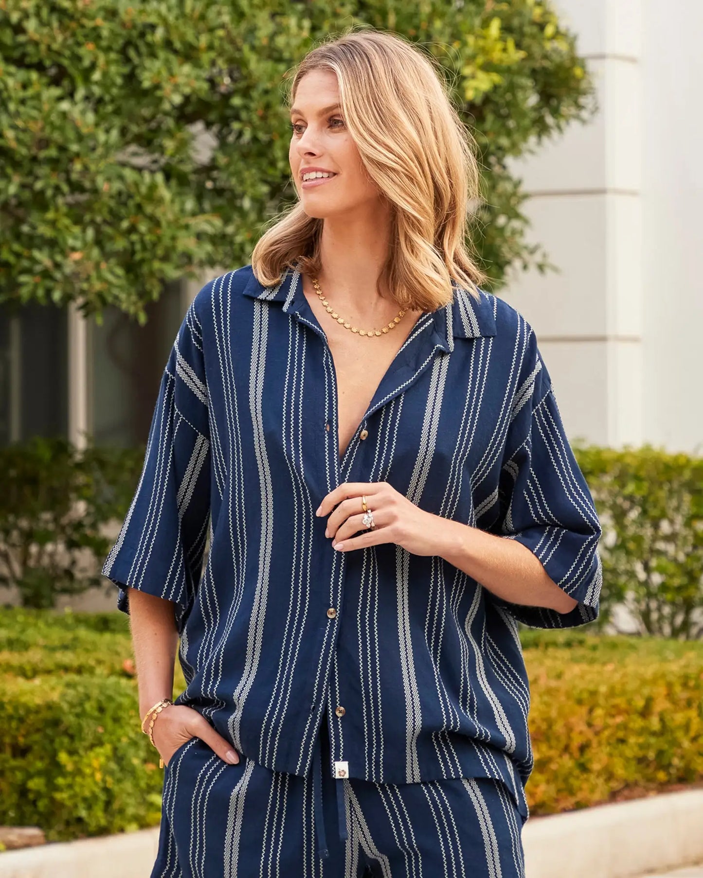 A female model posing candid outside wearing the Okanui 3/4 Sleeve Shirt in navy.