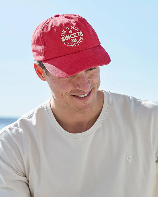 A male model wearing the Okanui Stamp Trucker cap in Washed Rose