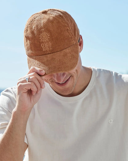 A person wearing the Okanui sunburst corduroy trucker cap in San