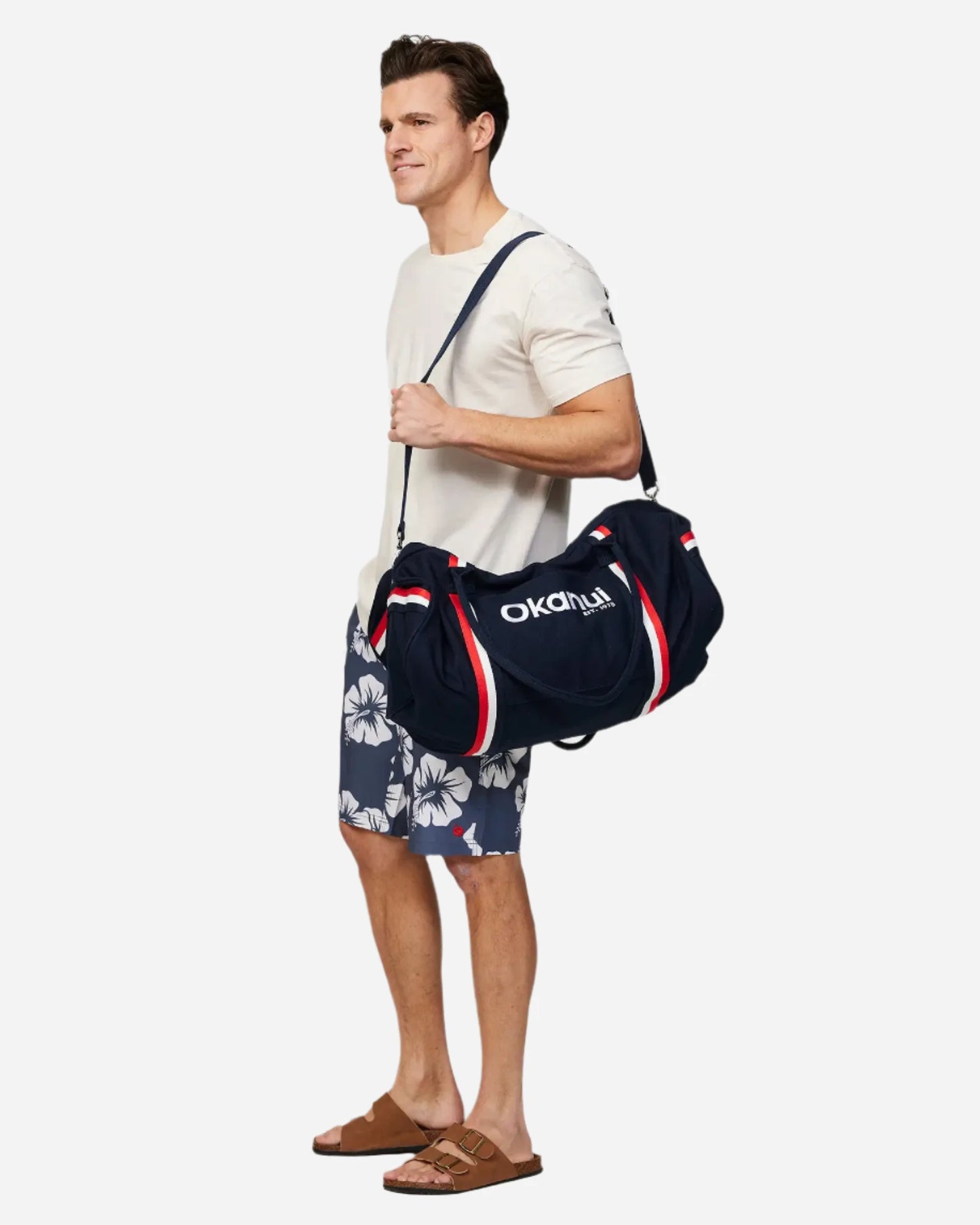 A person holding the Okanui Classic Duffle Bag in Navy in his left shoulder