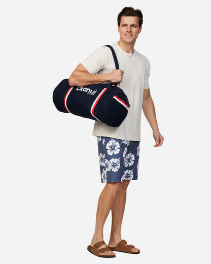 A person holding the Okanui Classic Duffle Bag in Navy in his right shoulder