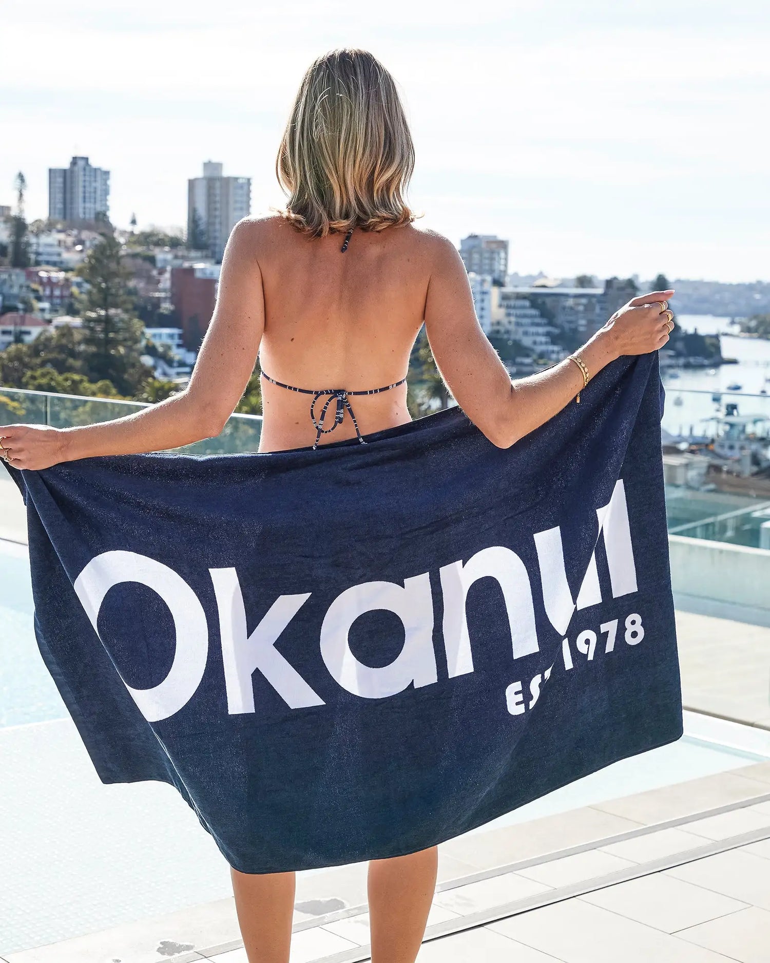 A female model covering her back with the Okanui Beach Towel