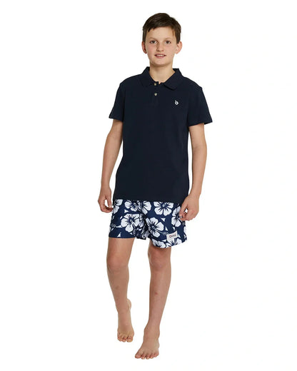 A full body image of a boy wearing the Okanui classic polo shirt in Navy color, crafted from 100% cotton with a stepped hemline cut for style