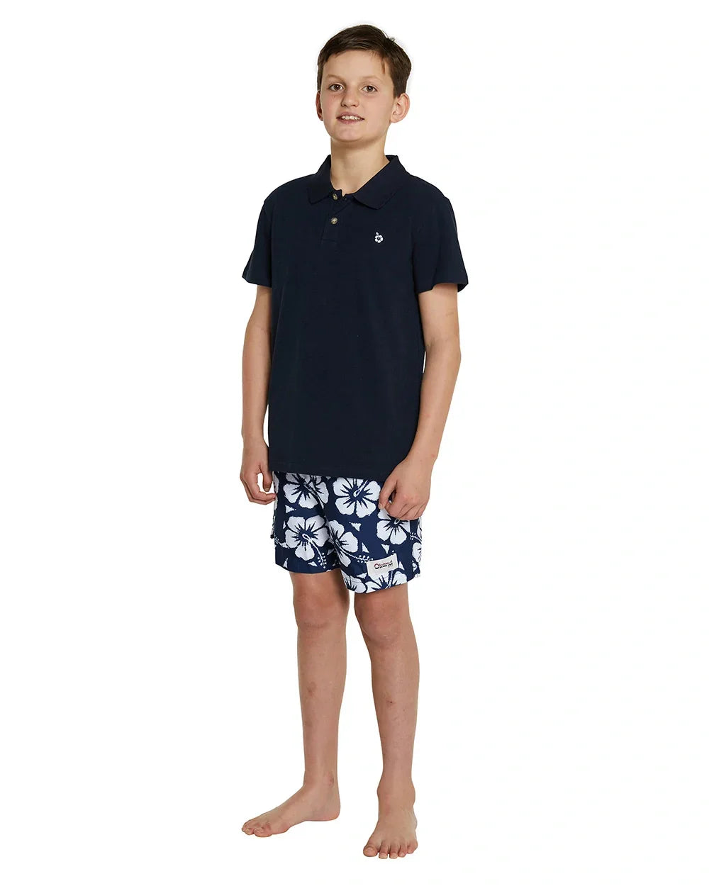 Full body photo of a boy wearing the Okanui classic polo shirt in Navy color crafted from 100% premium cotton and featuring a stepped hemline cut for style