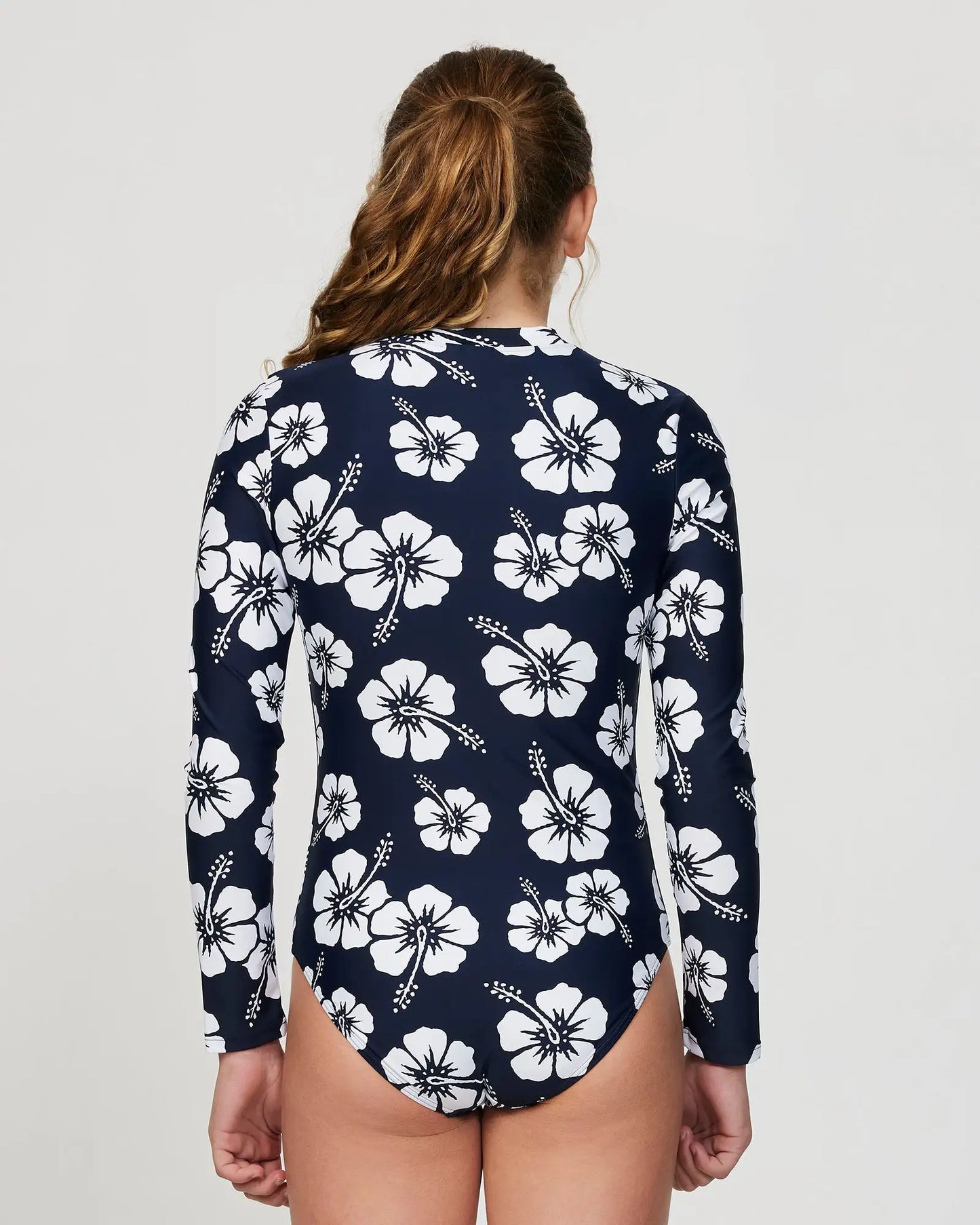 Close up back view of a girl model wearing the Okanui long sleeve one piece swimsuit for girl in Hibiscus Navy